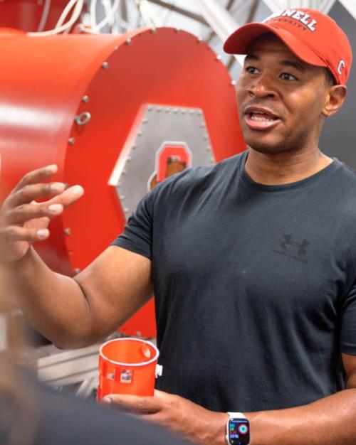 Person in Cornell cap speaks enthusiastically to a small group