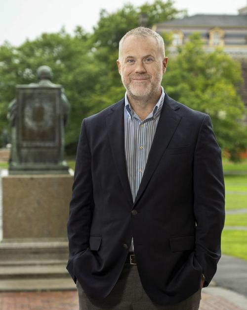 		Dean Peter Loewen posing behind the A.D. White statue on the Arts Quad
	