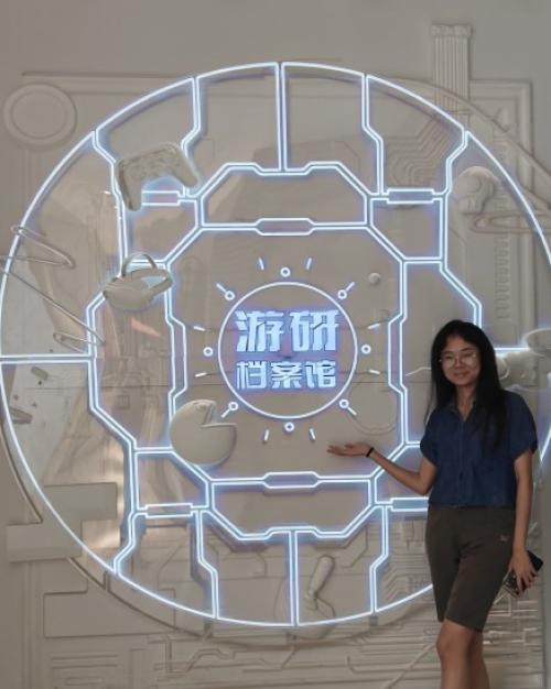 		Person standing in front of a large glowing neon circle outline with Chinese characters in the center
	