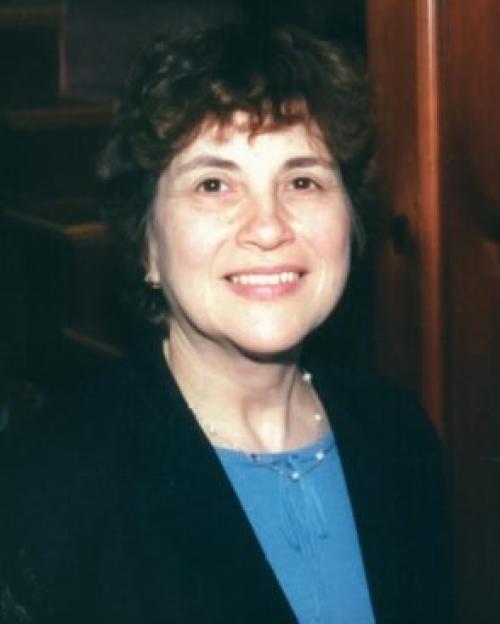 Deanne Gebell Gitner, smiling, with short black hair, a jacket and pearl necklace