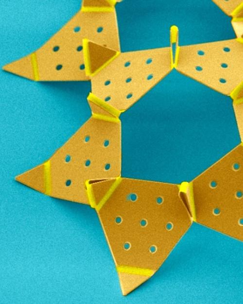 		yello triangles with holes punched in them, all conntected, on a blue background
	