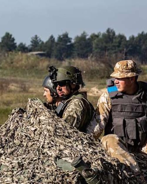 		A few solders in camoflauge in a field
	