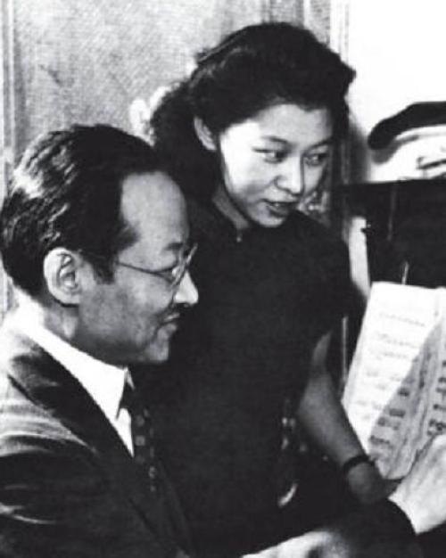 		two people looking at sheet music that's sitting on a piano
	