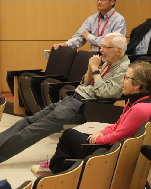 		Person sitting in an auditorium chair but very casually, with a smil in his face
	