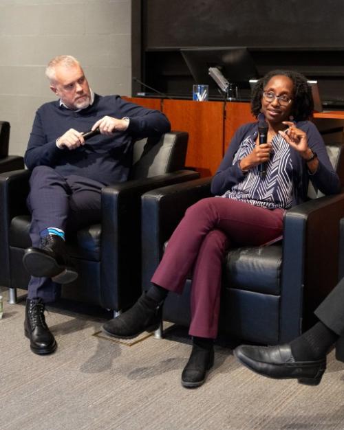 		The panelists sitting in arm chairs, all three looking at Prof. Jamila Michener talking into the microphone.
	