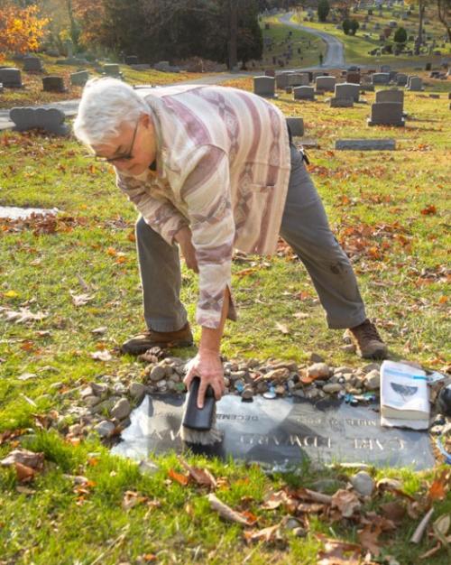 		Person bending over to sweep a flat grave marker
	