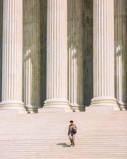 		Woman in business clothes walking down the steps of the Supreme Court with the tall columns behind her.
	