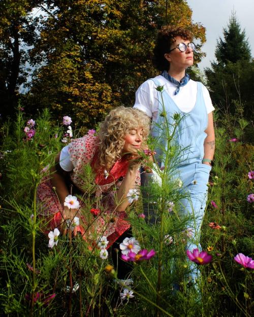 		Two people -- characters in a play -- stand in a field full of flowers
	