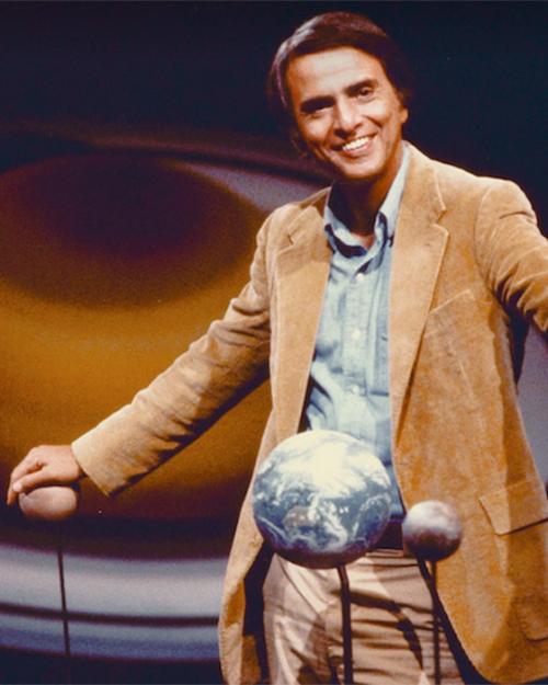 		Person in late-70s chic tan sport coat, touching models of planets
	