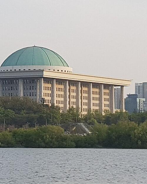 		Public building with a green domed roof, beside a river
	