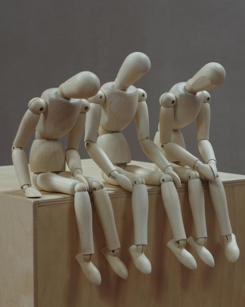 Three wooden figures posed to look tired