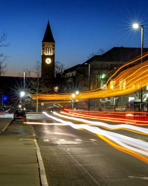 		Orange red and white horizontal streaks of light under a dark blue sky, showing automobile traffic in motion at night
	