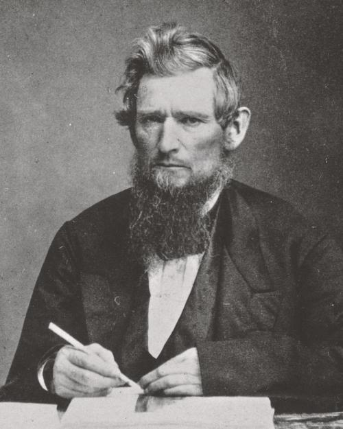 		Black and white historic photo of Ezra Cornell, frowning and holding a pen. 
	