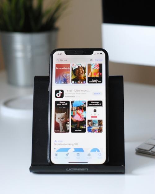 smart phone on a stand on a desk, showing TikTok home page