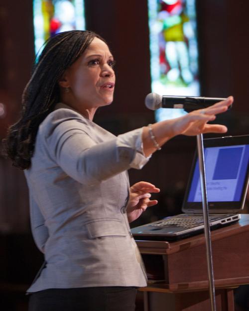 Person speaking at a podium with stained glass windows in the background