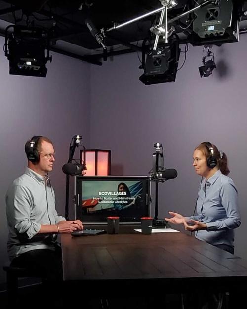 		Two people sit at a table in a recording studio
	