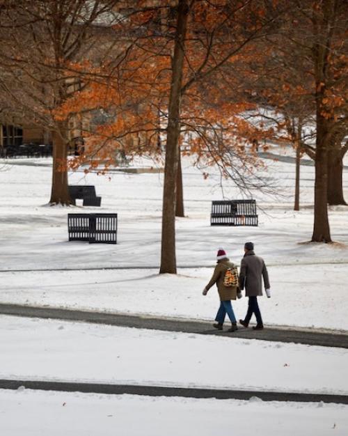 		Two people walk across a snowy college quad
	