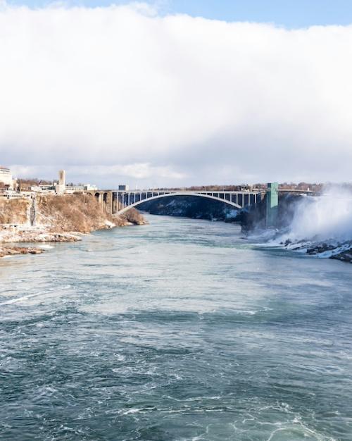 A wide river dividing two banks with a bridge in the distance