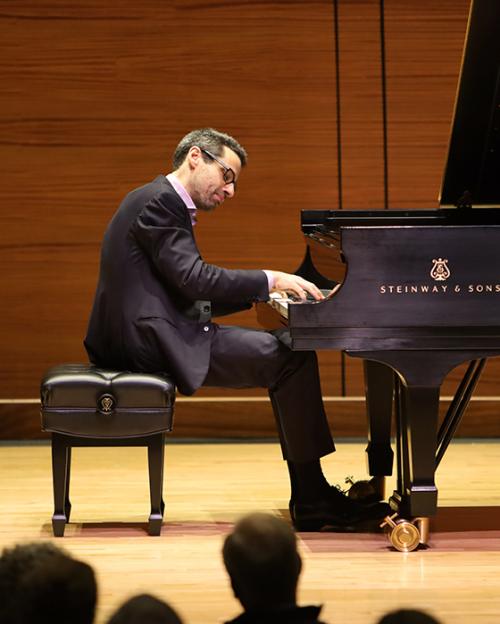 Person sitting at a grand piano, playing thoughtfully