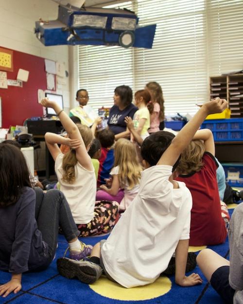 		Several children sit on a rug in a classroom
	