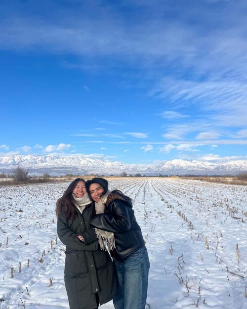 two woman hugging in a field full of snow