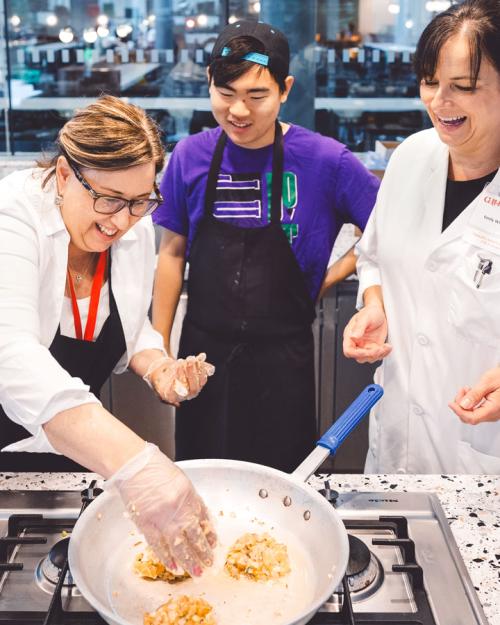 three people cooking over a stove