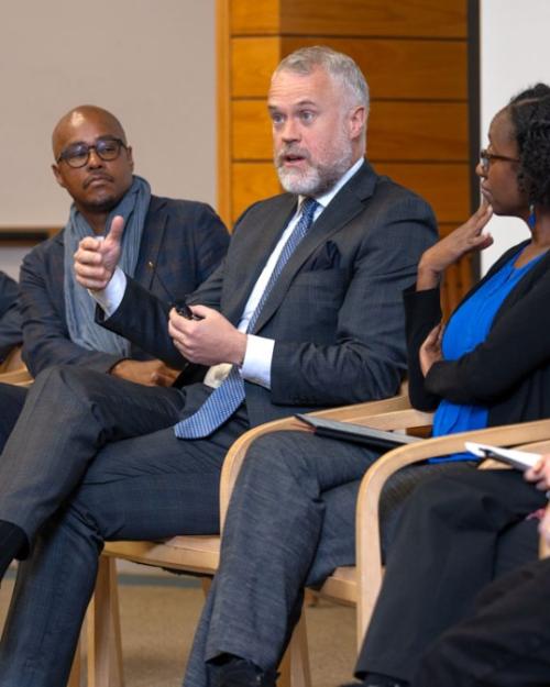 Six people sit in a row, during a panel discussion event