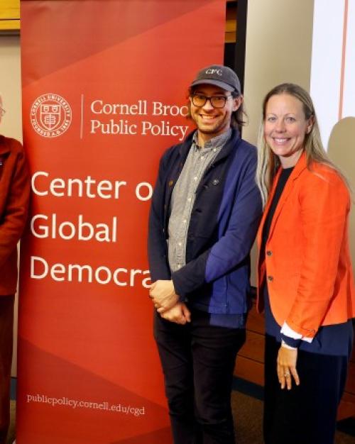 		Five people stand near a sign that says "Center on Global Democracy"
	