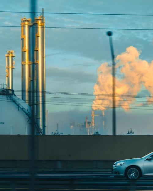 		Car driving past a factory belching smoke
	