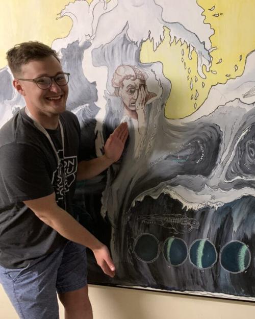 		Two people laughing near a large poster showing a wave
	