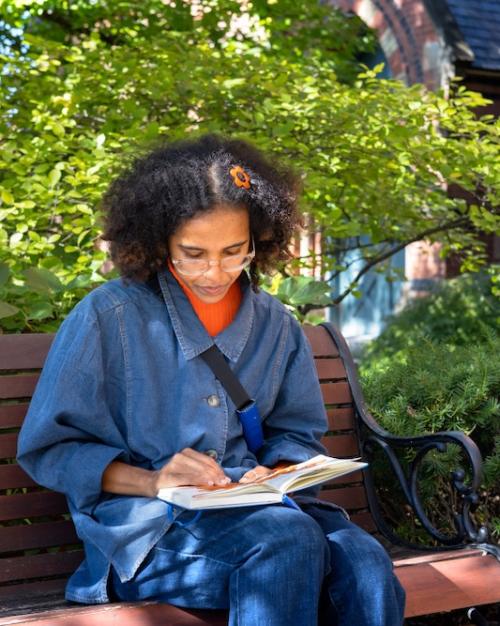 Person sitting on a bench under a tree, reading a book
