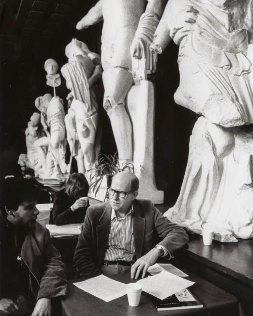 A.R. Ammons talking to a student in the old Temple of Zeus cafe, with large replicas of ancient sculptures in the background