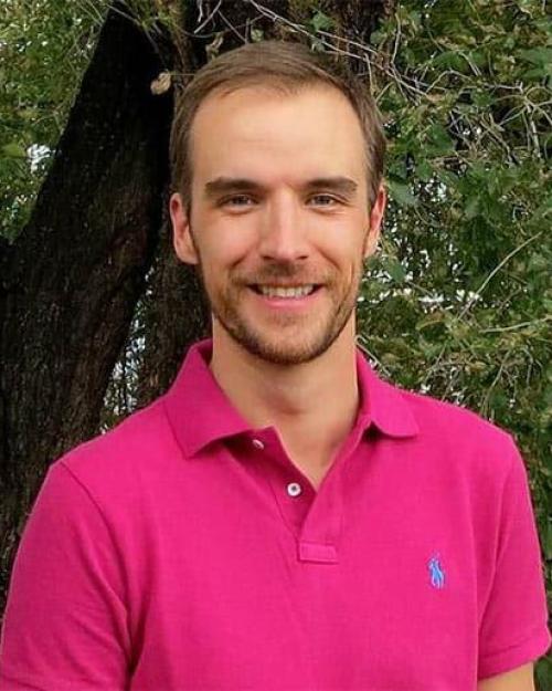 Brad Ramshaw, smiling, with very short mustache and beard, in a polo shirt in front of a tree