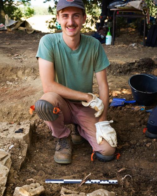 person kneeling by a dig site