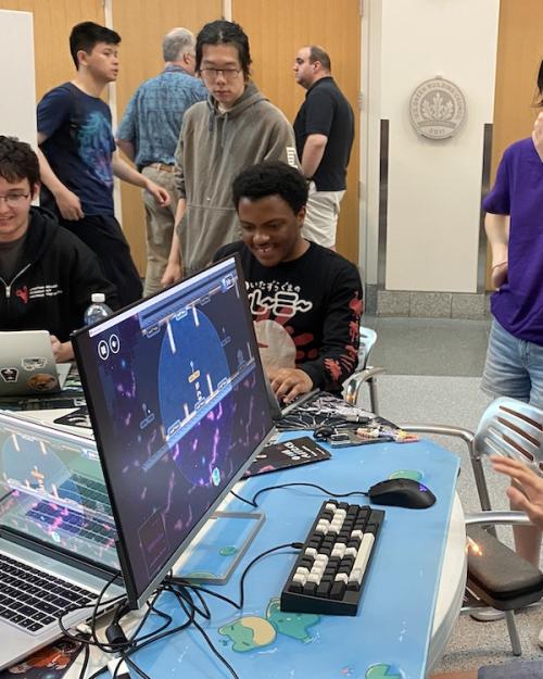 		Several people gathered around a table with computer games
	