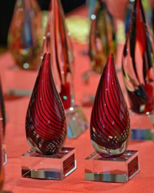 Glass figures shaped like a teardrop on top of a square glass base, red with black lines swirling down in parallel