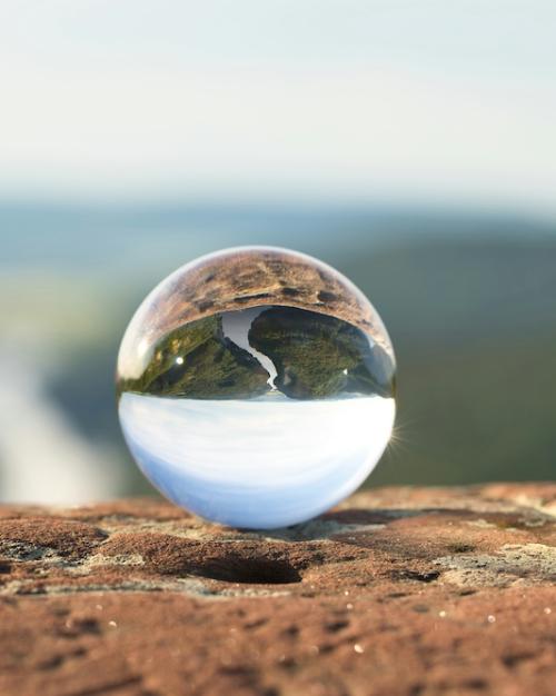 		crystal ball reflects a view of a river, upside down
	
