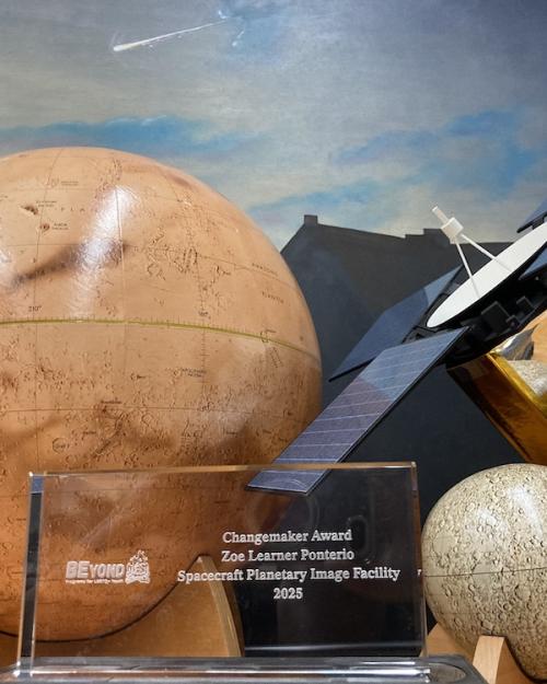 Rectangular glass award set among model planets on a table