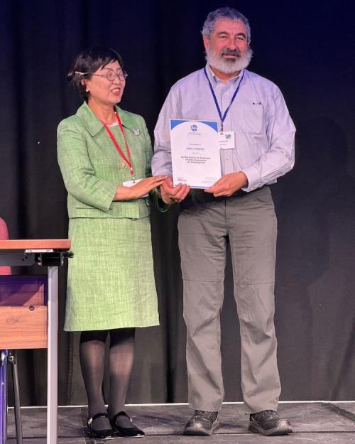Two people standing on a stage, holding a certificate between them