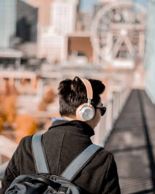 Person wearing pink headphones, walking outdoors in a city
