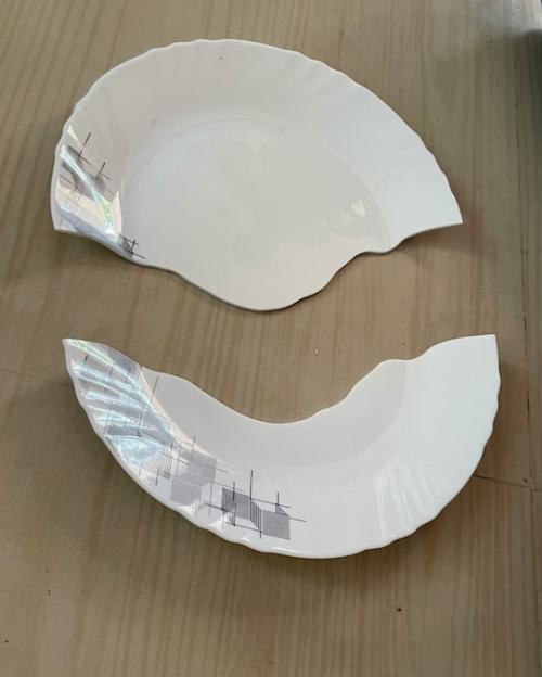 White plate, broken in half on a wood floor
