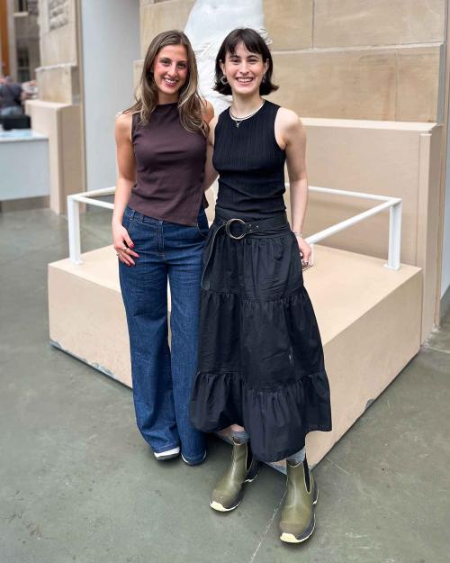 		two people standing in front of a statue
	