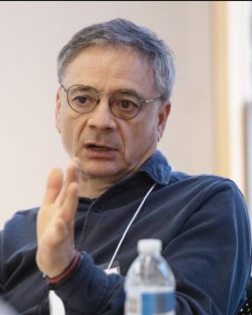Older man with glasses and gray hair talking with his hands.