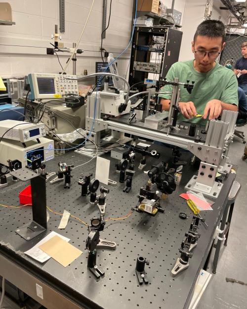 Man with glasses and t-shirt working on complex electronic table-top machine