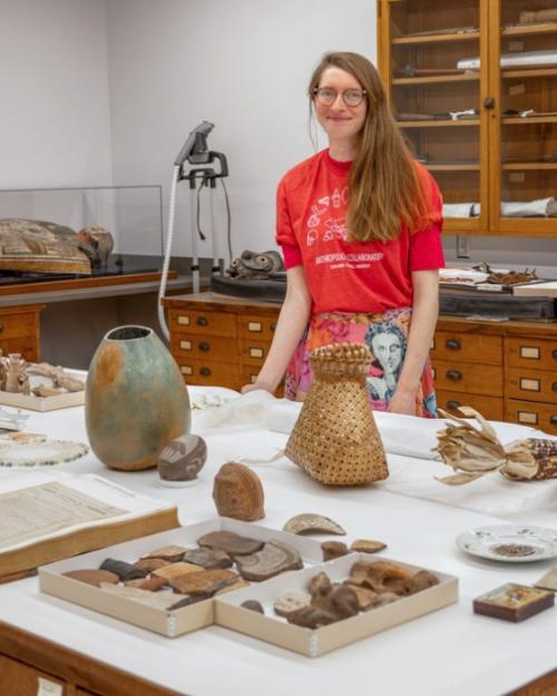 		Person standing behind a table covered with artifacts
	