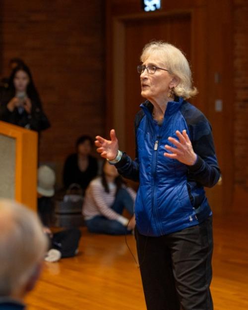 Person speaking in front of an audience in a packed auditorium