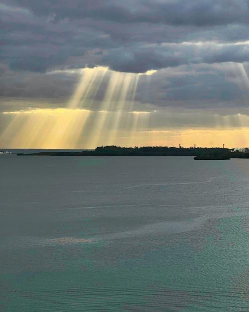 Sun beams shoot through heavy clouds over a bay
