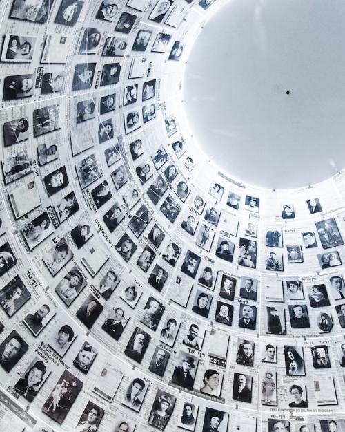 		hundreds of black and white portrait photos on a wall leading up to a light grey dome
	