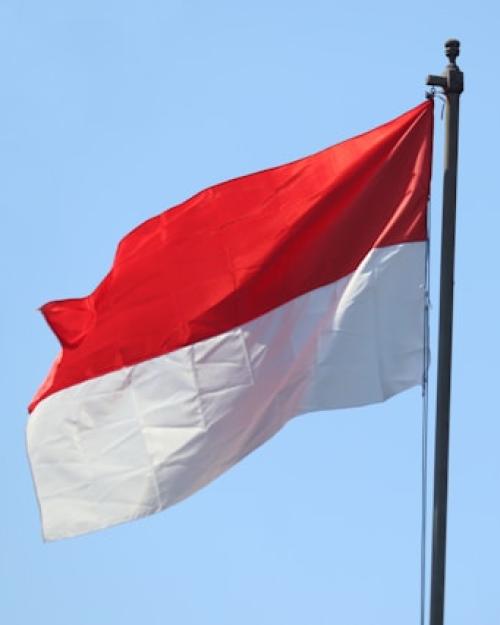 Flag with broad red stripe on top and broad white tripe on bottom on flagpole against a blue sky.