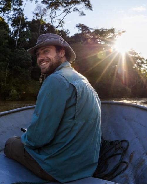 Person in a small boat on a river, turning around and smiling